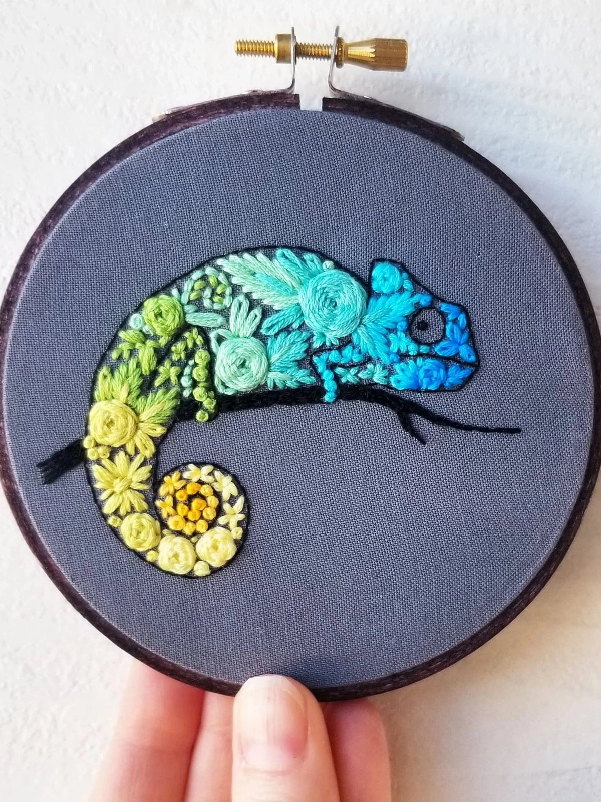 The *Pre-Order* 4" Beginner Chameleon Embroidery Kit by Jessica Long Embroidery features a vibrant chameleon design with blue, green, and yellow flowers in a round hoop, ideal for beginner stitchers.
